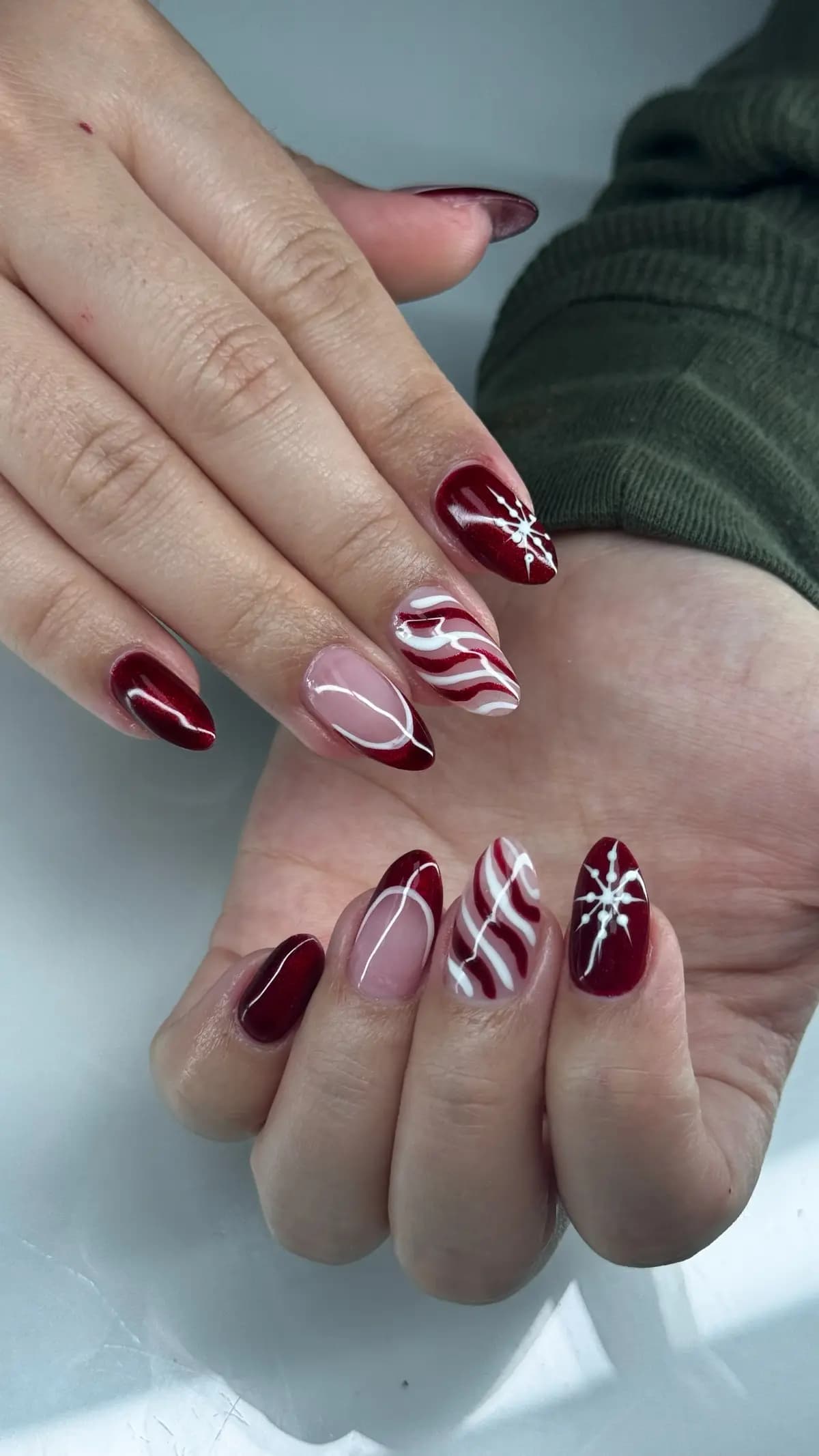 Red and white swirls painted over nude almond nails