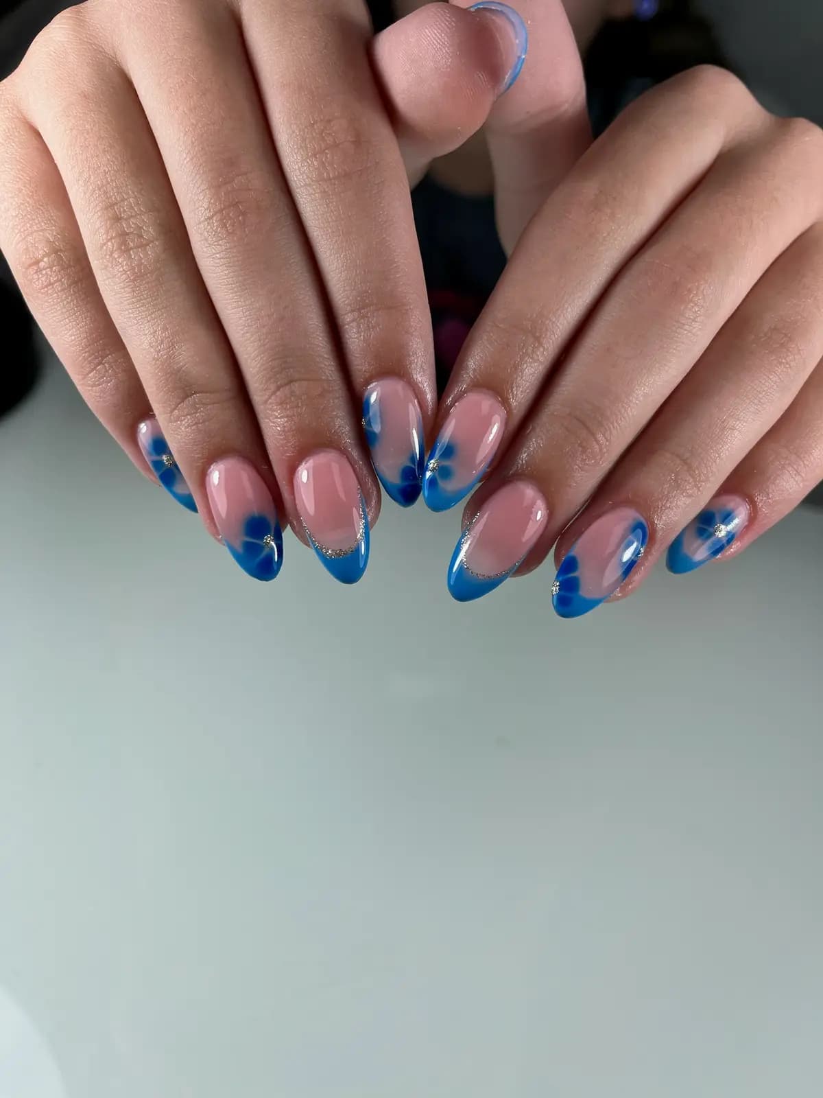 Blue french with tiny white flowers on almond nails