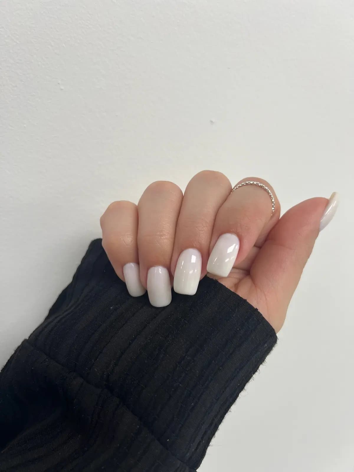 Short natural nails in a milky white tone, navy sleeve
