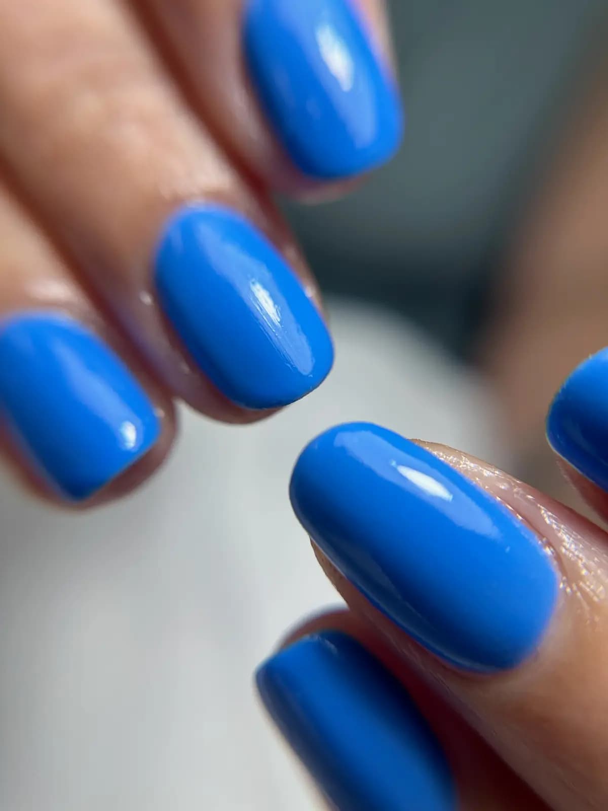 Bold blue gel manicure on rounded nails, close up