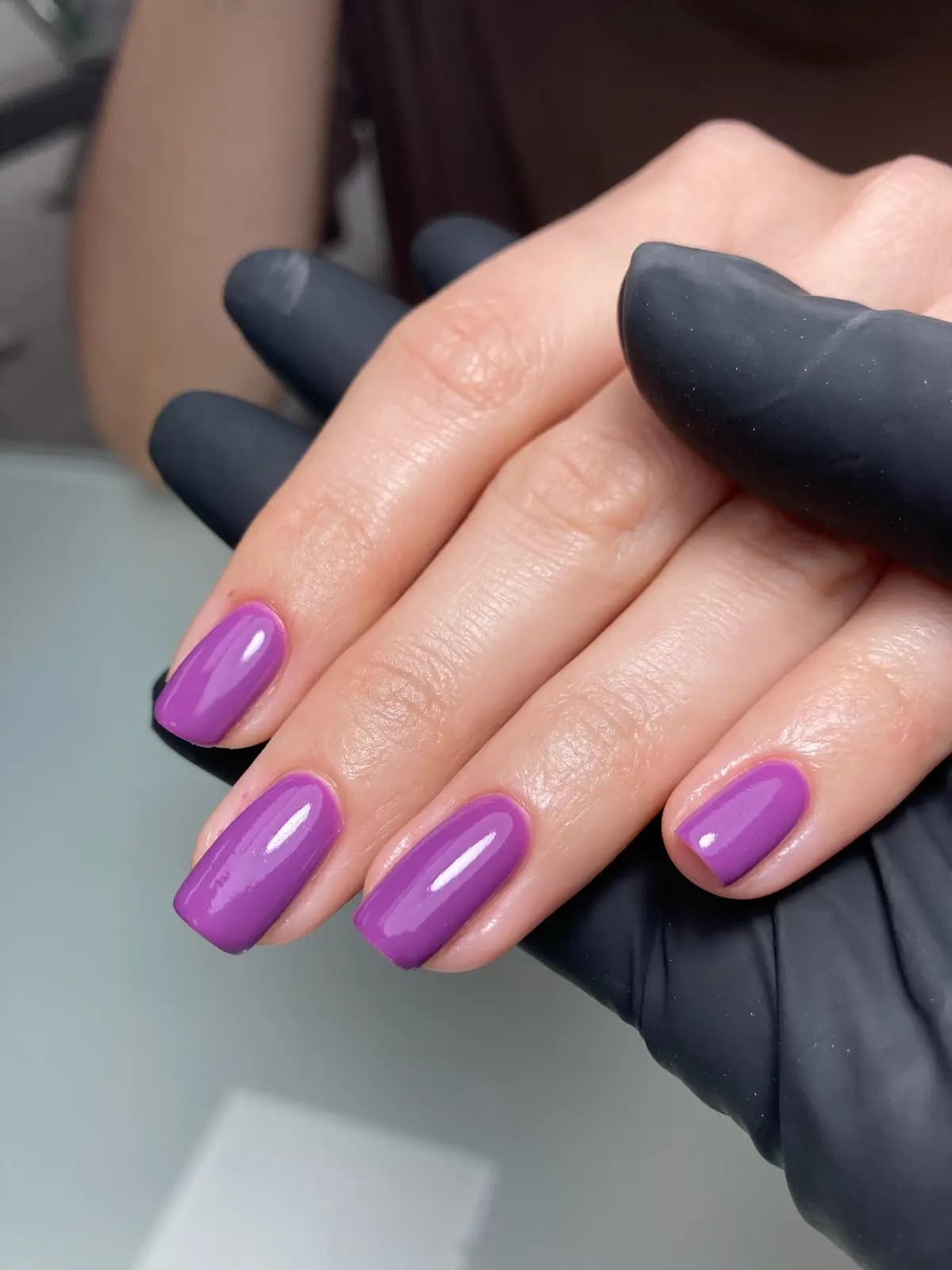 Short nails in orchid gel, both hands on the salon table
