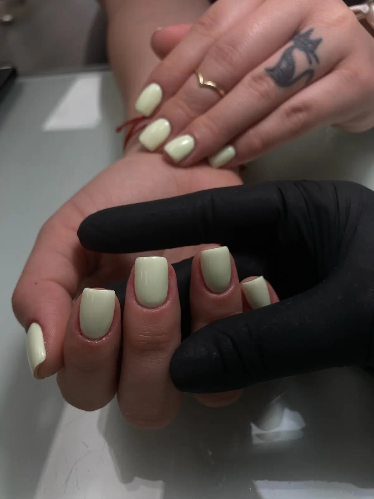 Long nails in pale yellow gel held by the gloved technician