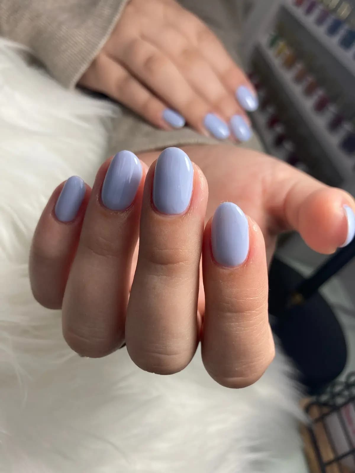 Short nails in lavender gel, hand resting on the salon table
