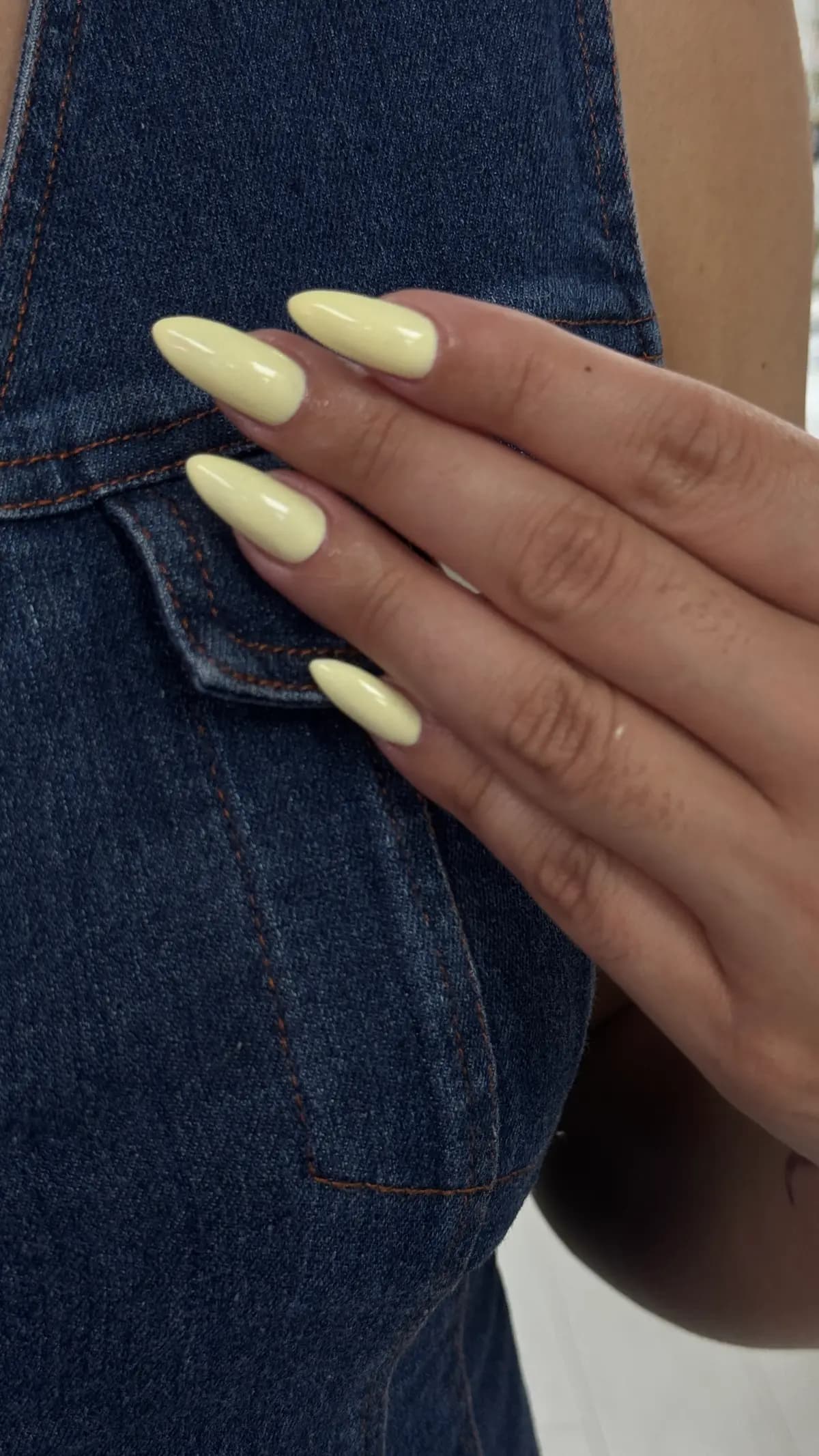 Butter yellow gel almond nails against denim