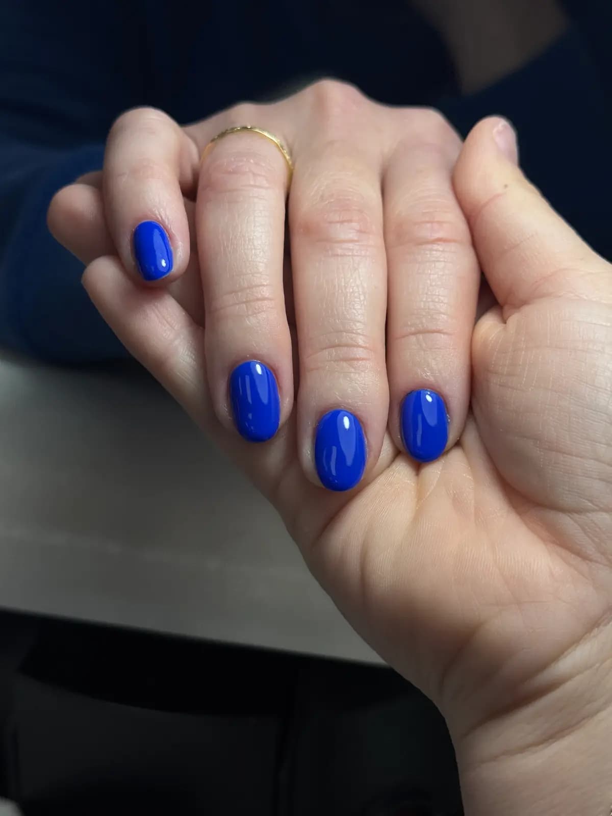 Short nails in royal blue gel, hand relaxed on the table