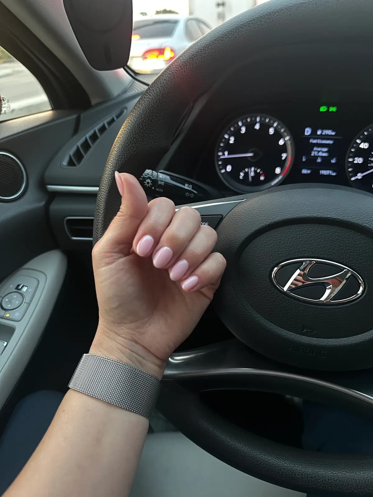 Pinkish nude nails at natural length, hand on the steering wheel
