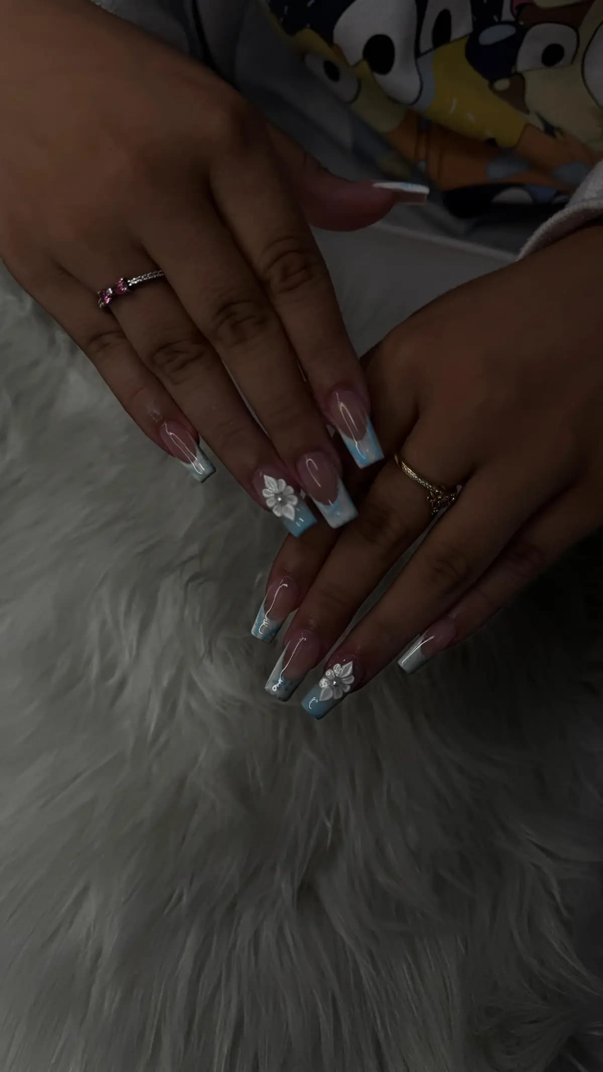 Long blue and white nails with 3D flowers on white faux fur