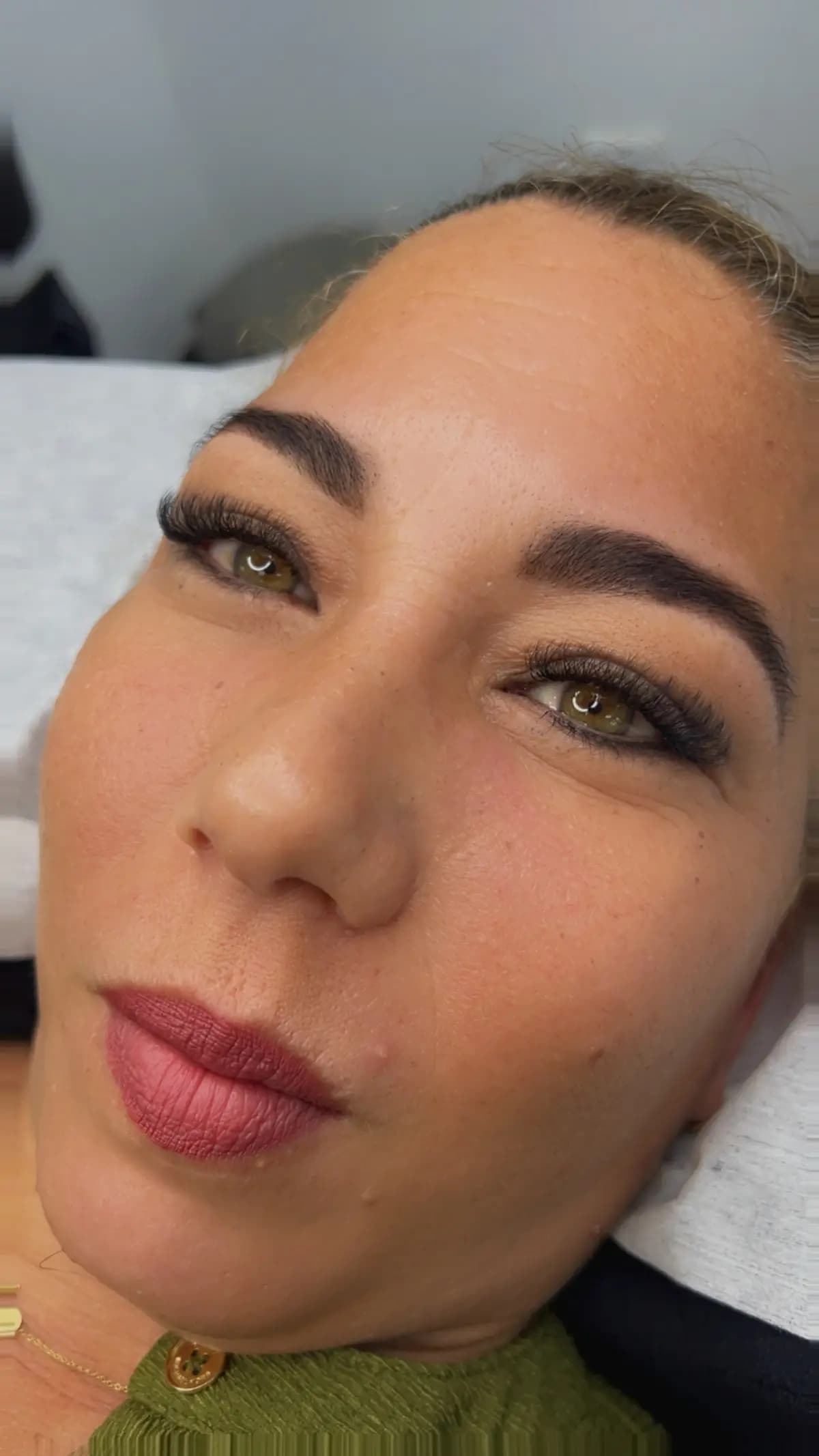 Client with shaped brows and extensions, sitting on the bed