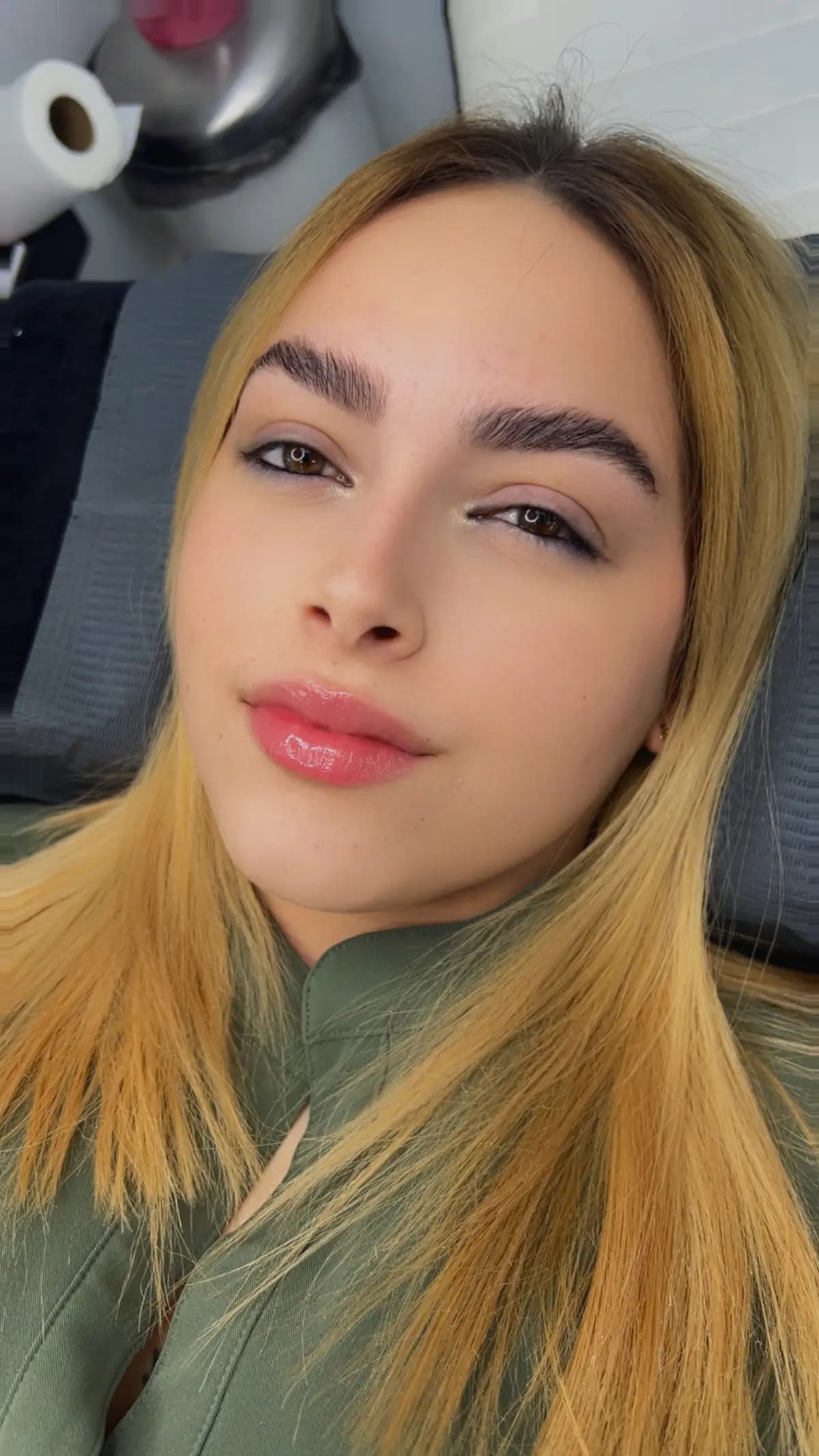 Blonde client with hybrid extensions and defined brows, on the treatment bed