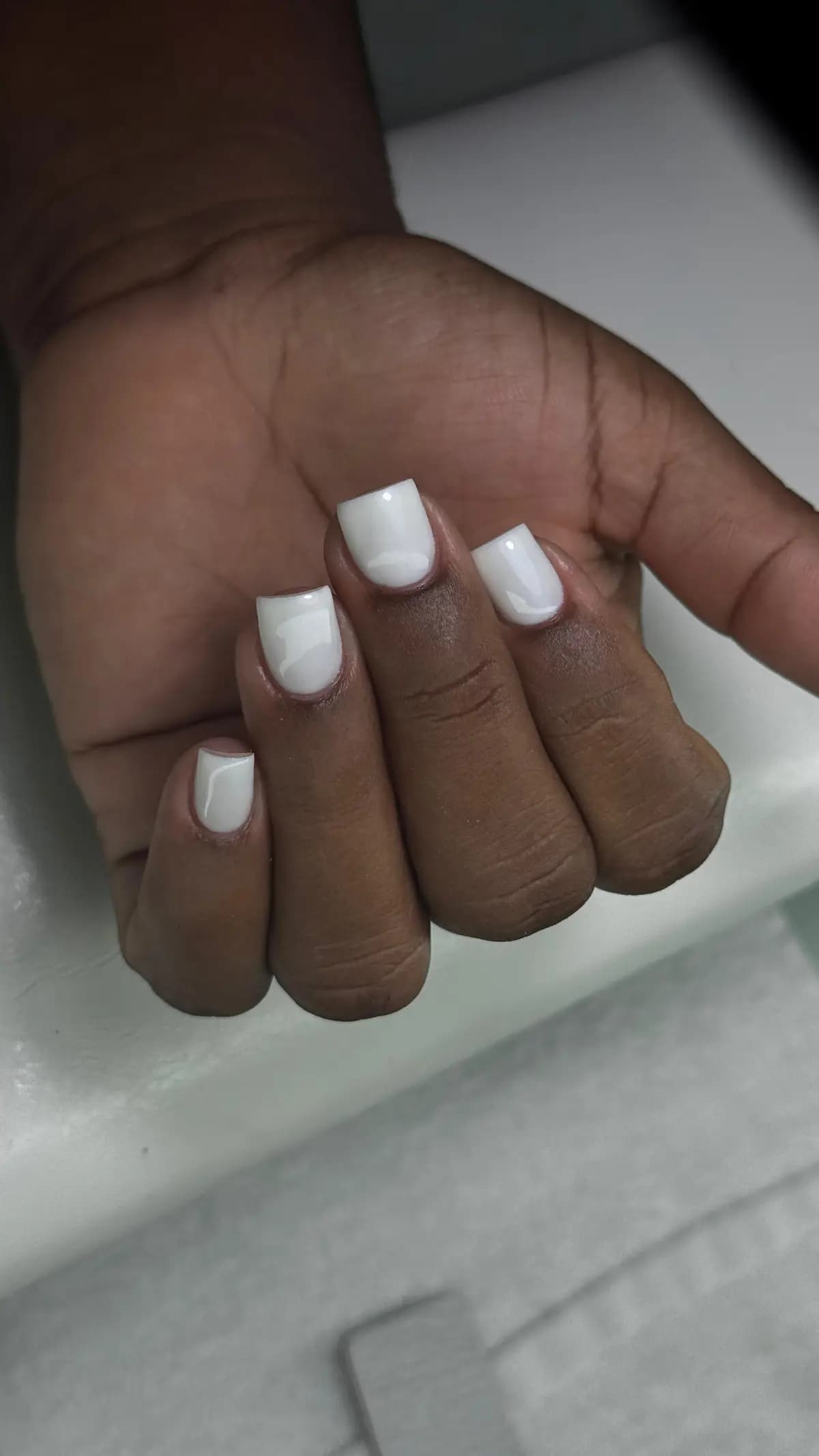 Short square nails in pure white, closed hand