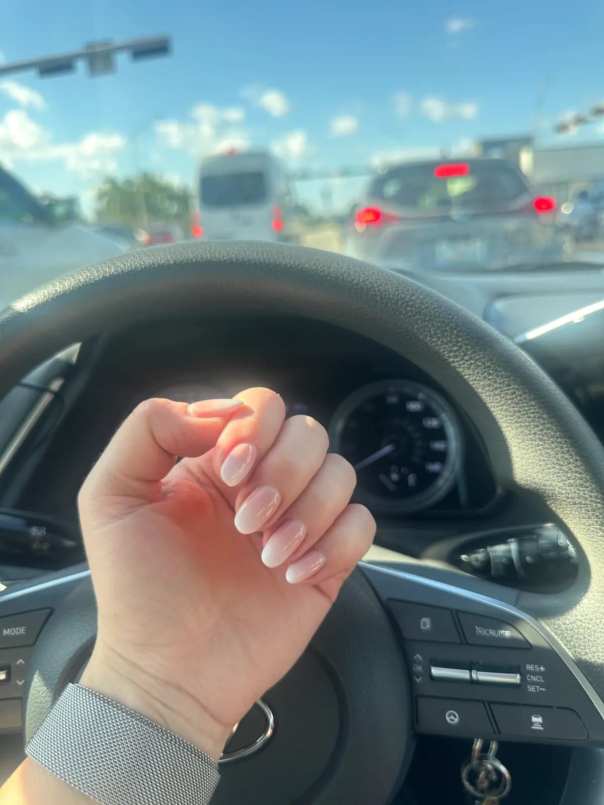 Medium-length nude nails, hand on the wheel leaving the appointment
