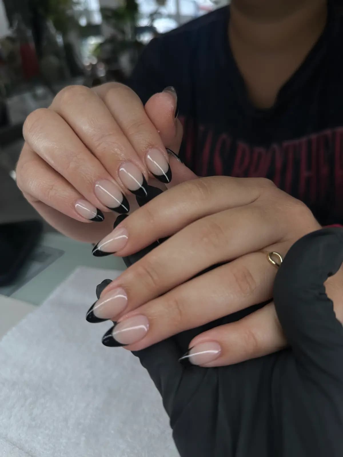 Black french tips on long almond nails, both hands
