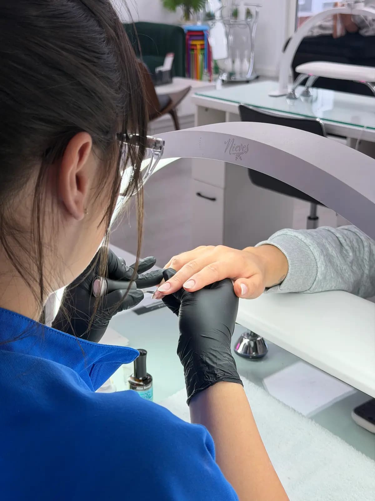 Technician removing product with an e-file at the manicure station