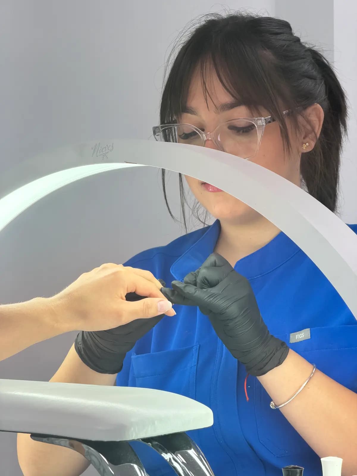 Technician applying polish in black gloves at the station