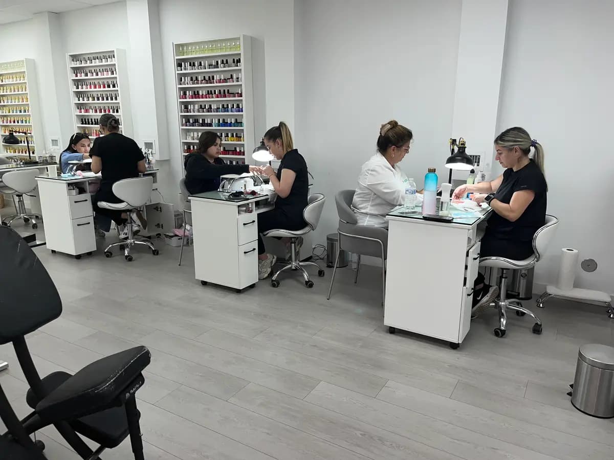 Manicure stations with technicians working and the polish wall behind