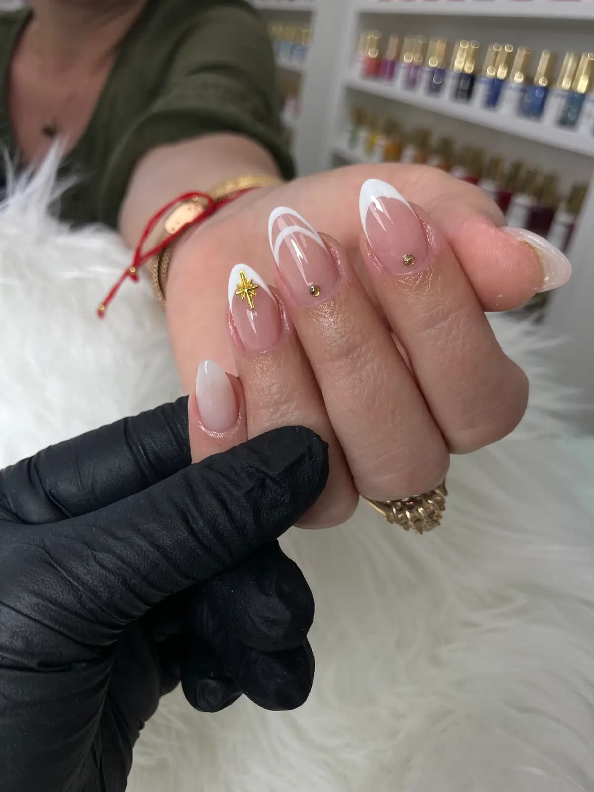 White french with gold detailing on almond nails, held by the technician