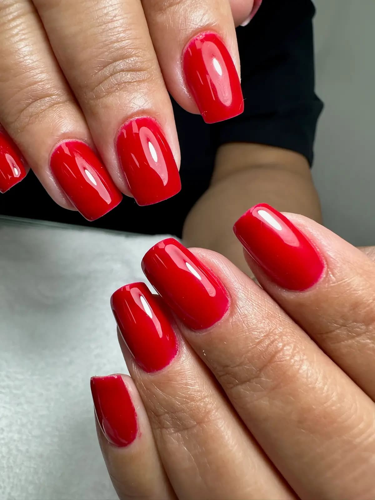 Bright red gel manicure with a mirror shine on short square nails