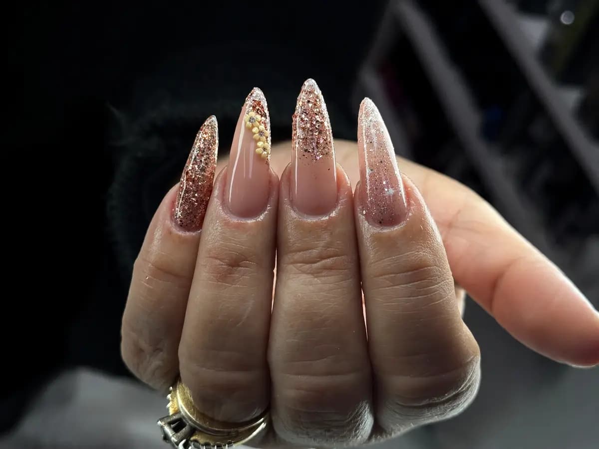 Long stiletto nails in nude with a champagne glitter fade