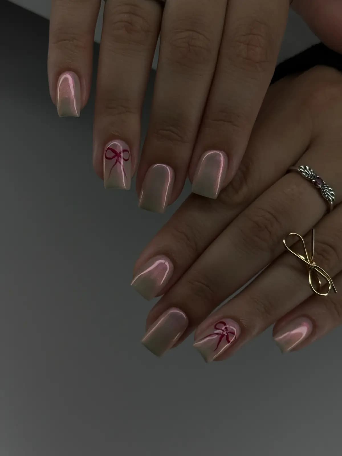 Nude nails with hand-painted red bows and thin rings