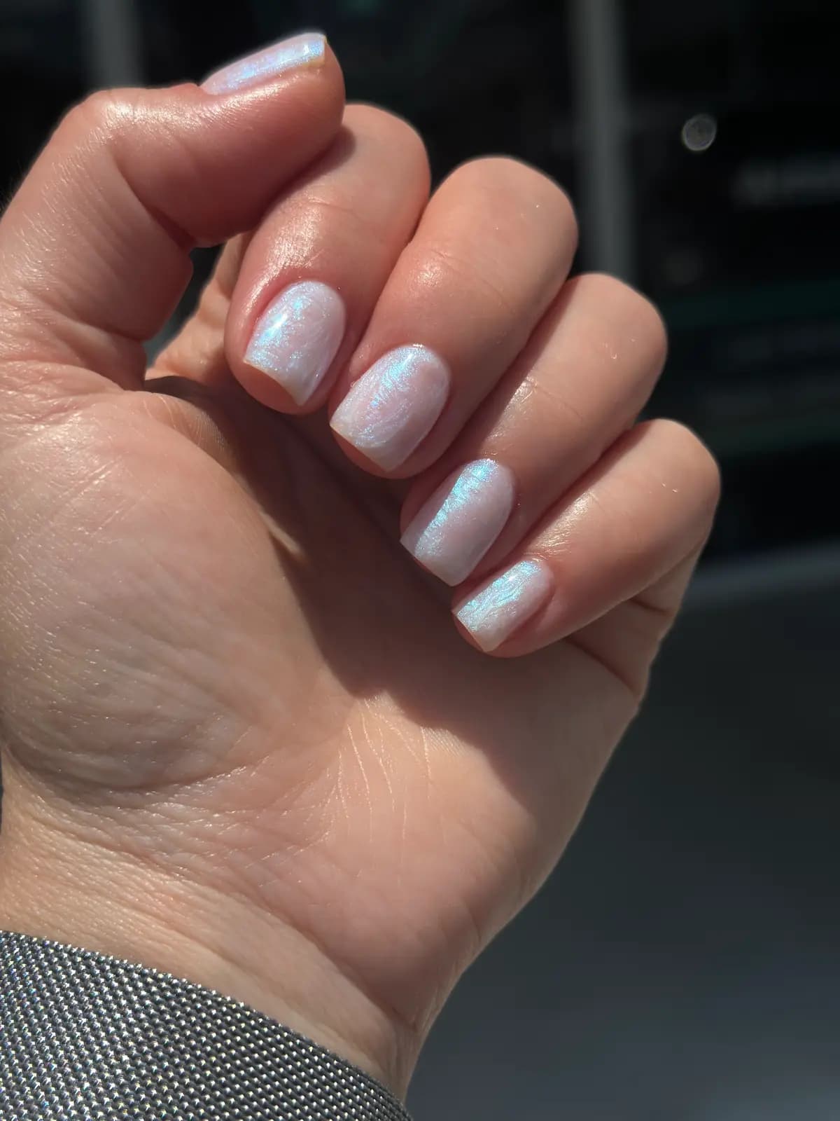 Short nails in white gel with a bluish sheen, closed hand