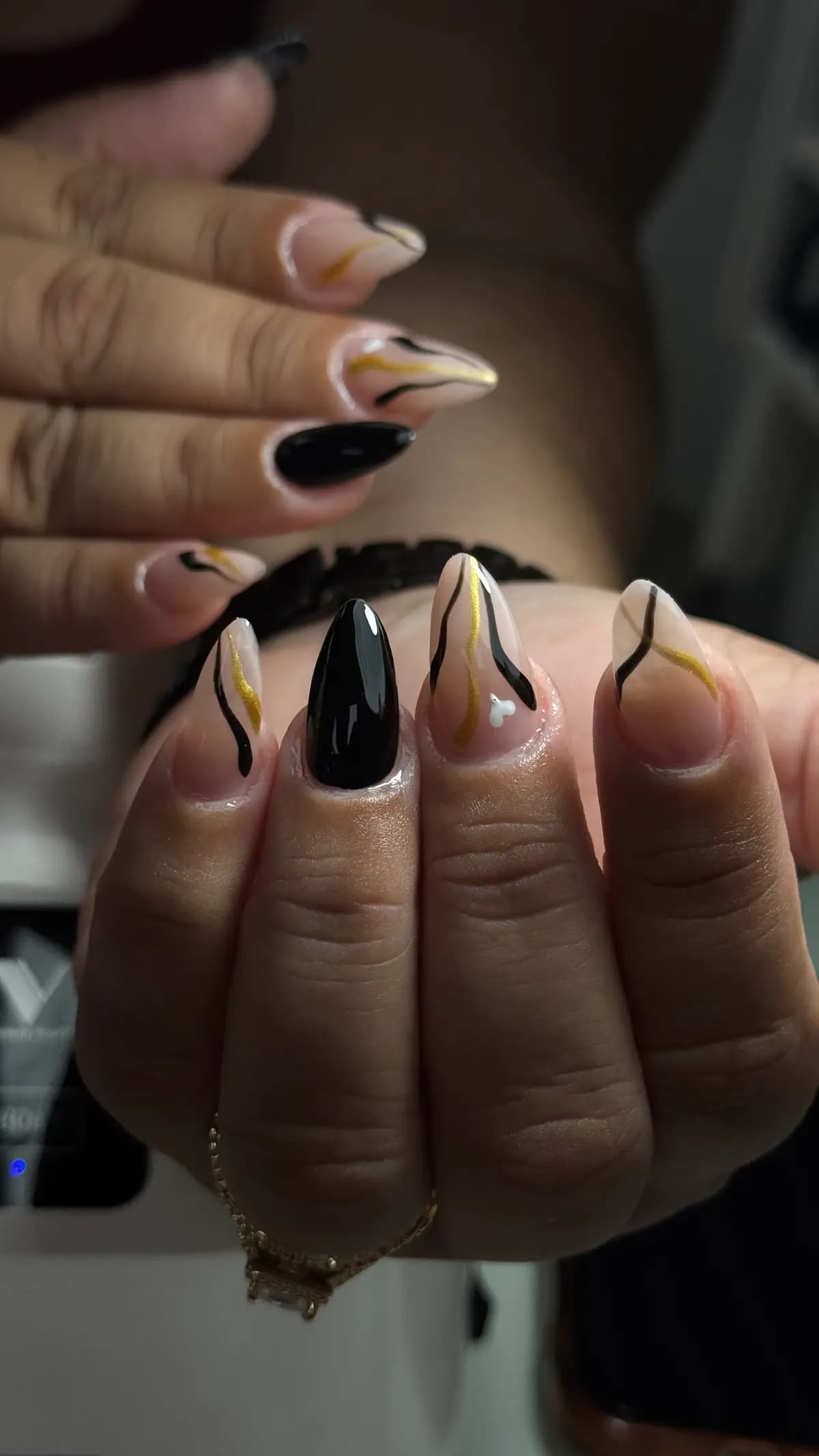 Stiletto nails with an abstract black and gold design on nude