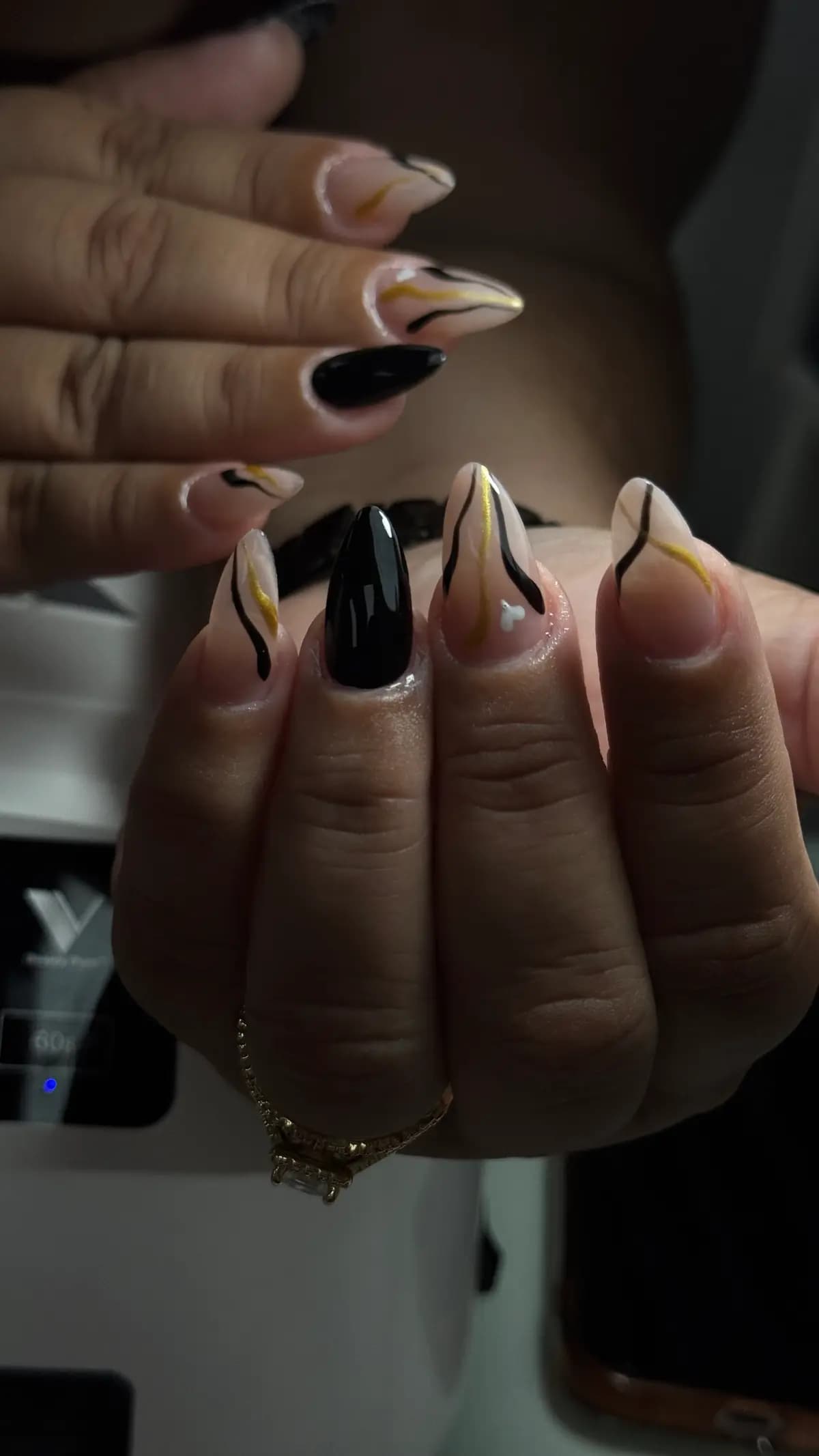 Stiletto nails with black and gold strokes and one solid black nail