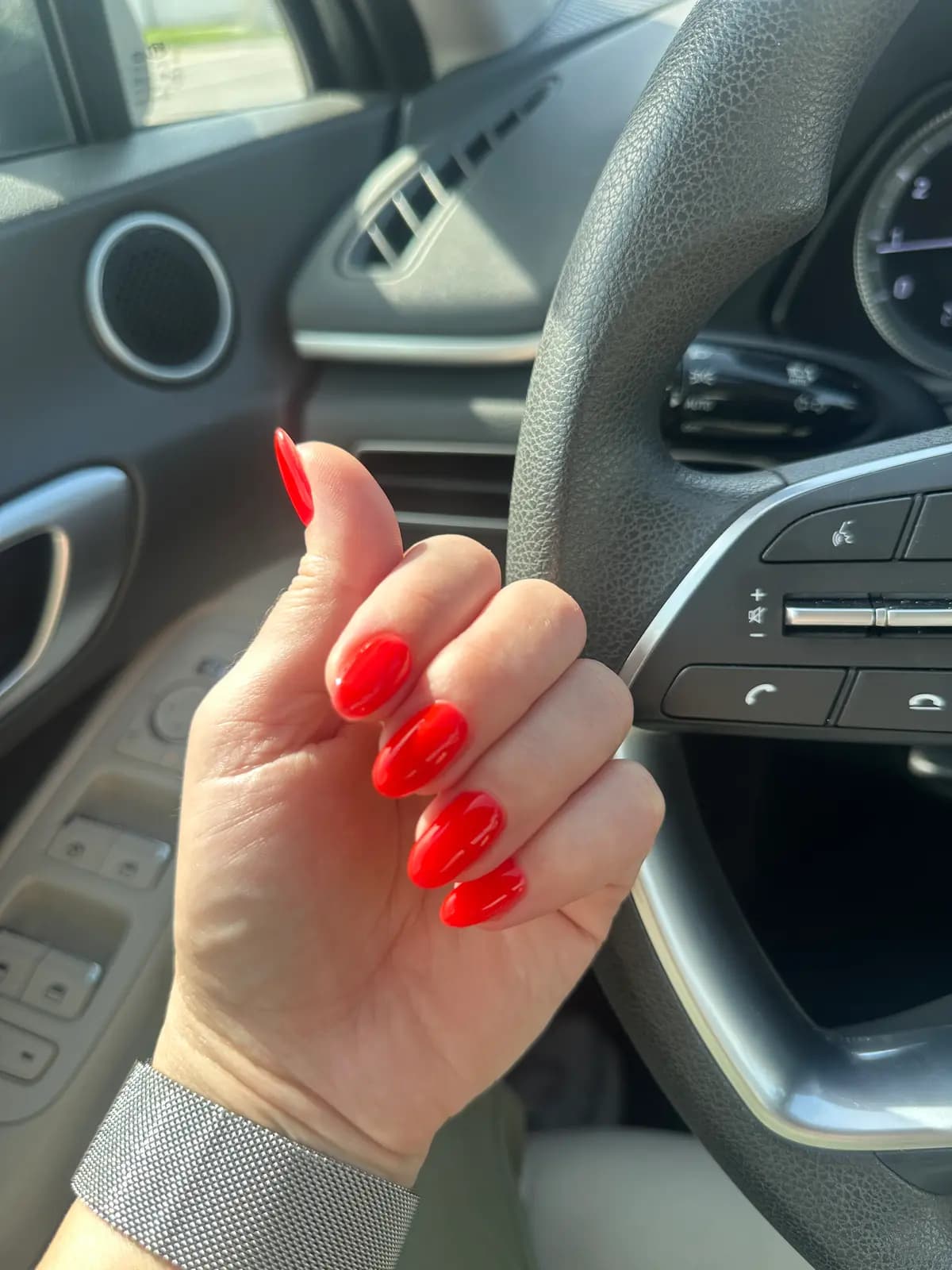 Bold red gel nails, close up inside the car