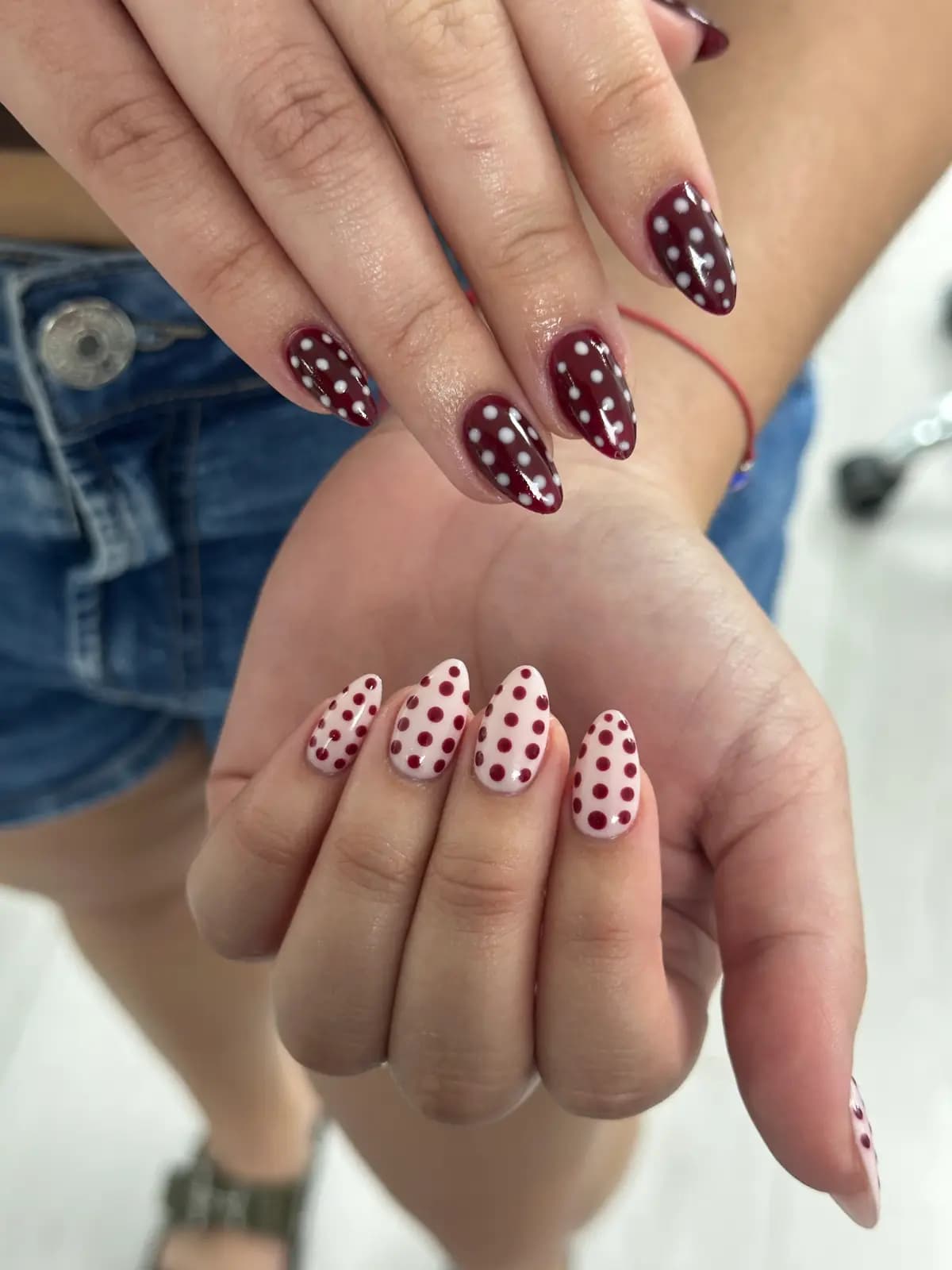Hand-painted burgundy polka dots on long nails, both hands