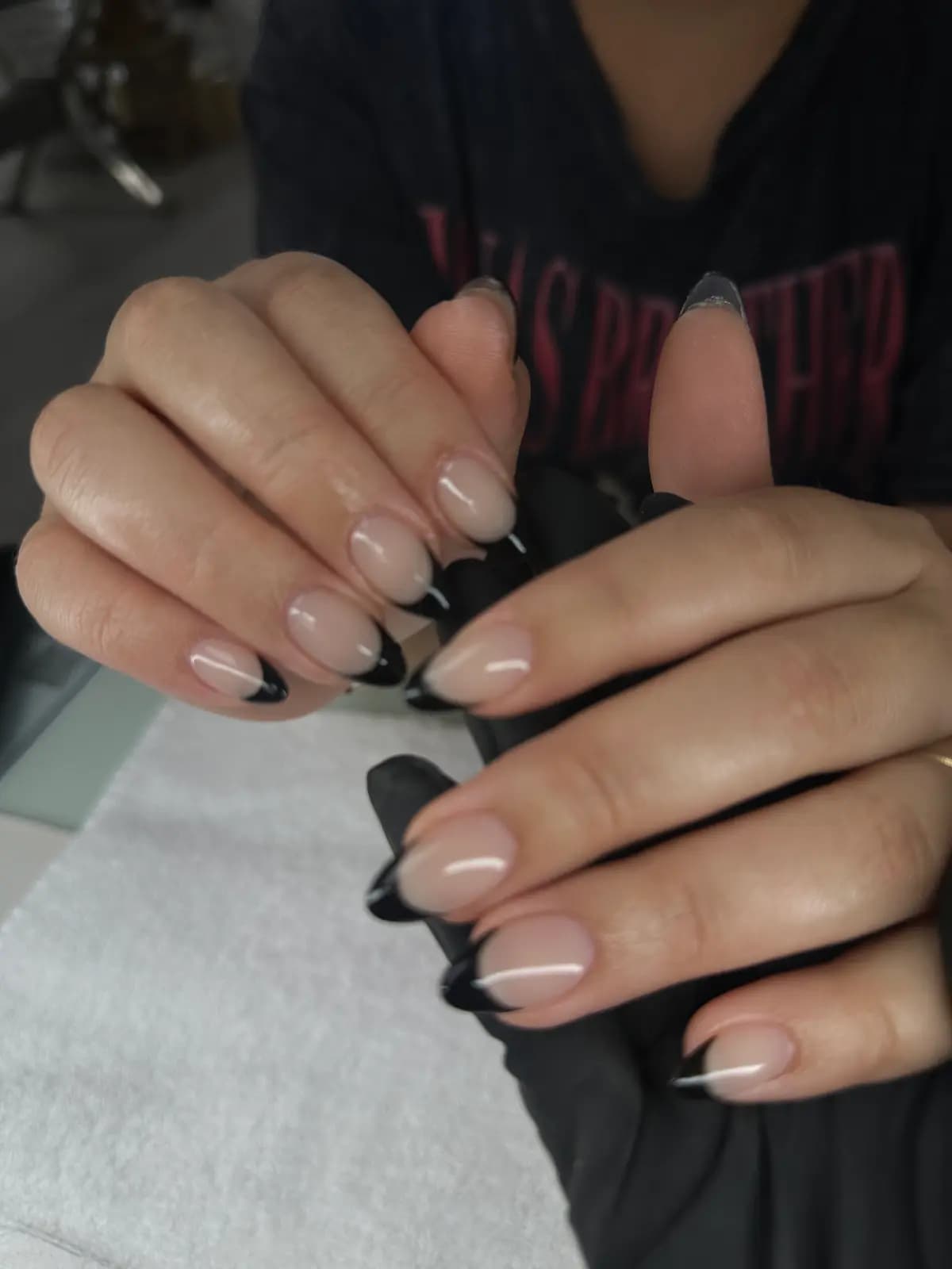 Thin black french tips on almond nails, relaxed hand