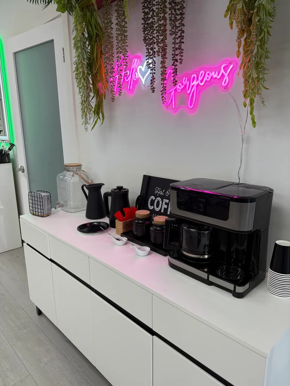 Coffee bar with the pink "Hey gorgeous" neon and hanging plants