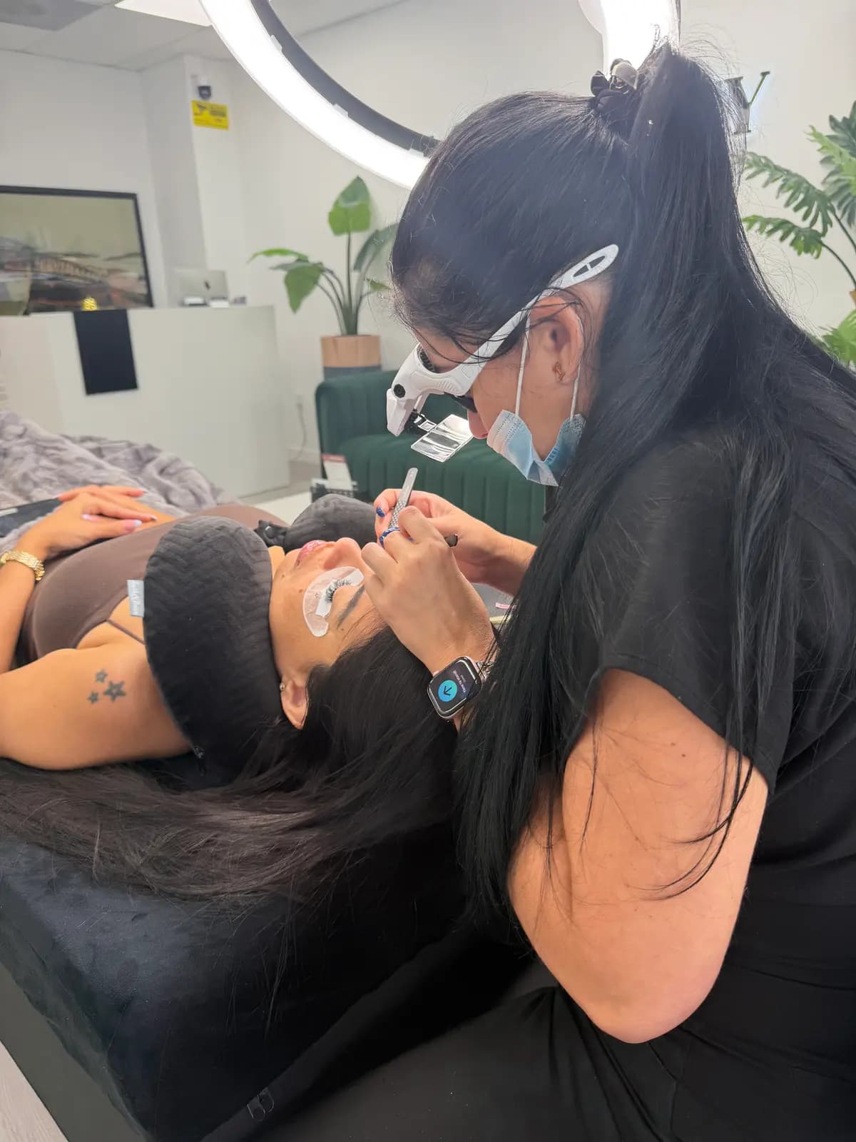 Lash technician working with binocular magnifiers on the client