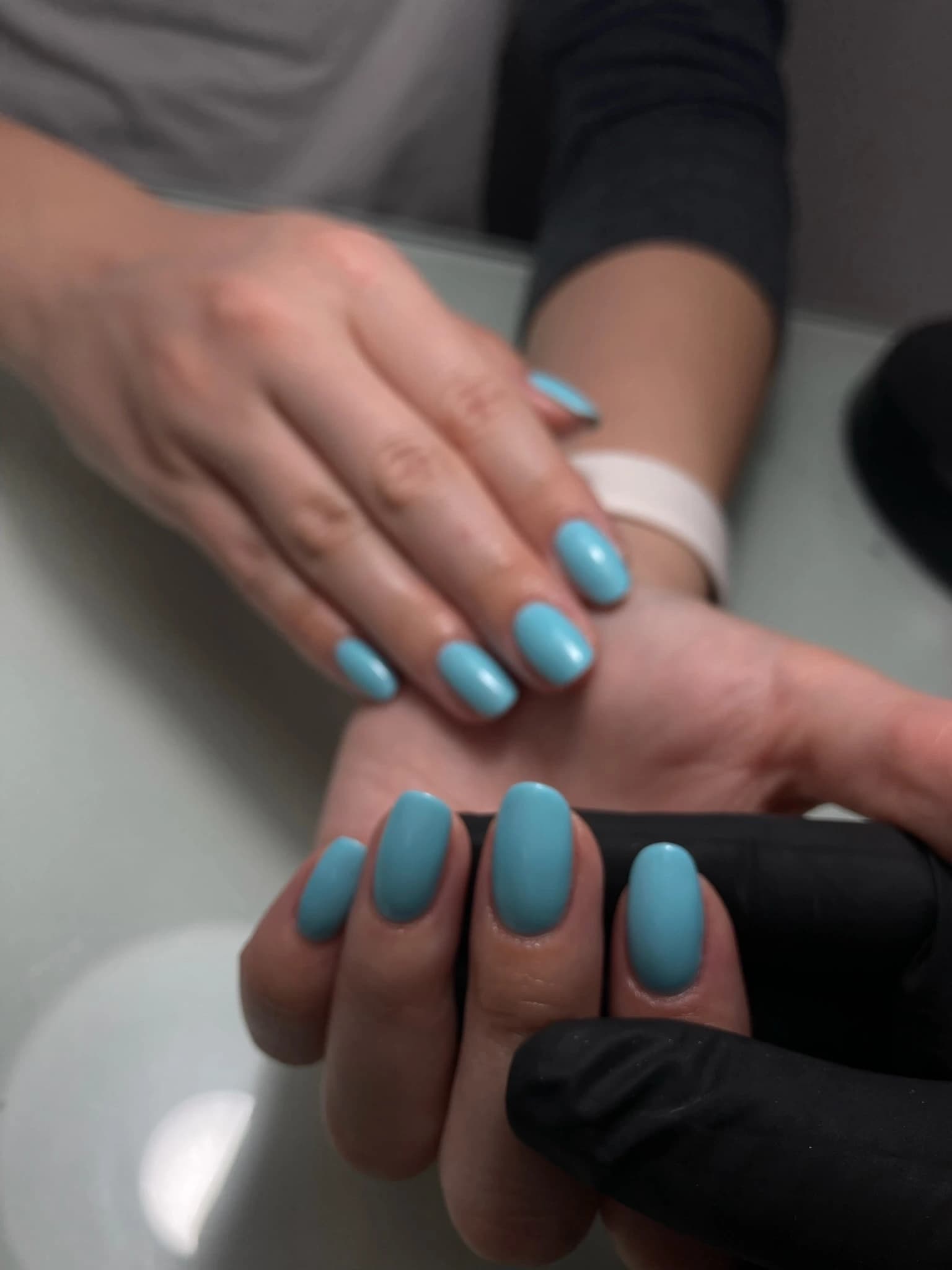 Sky blue gel manicure on short oval nails, applied by a gloved technician at Live Love Beauty Salon, Hialeah