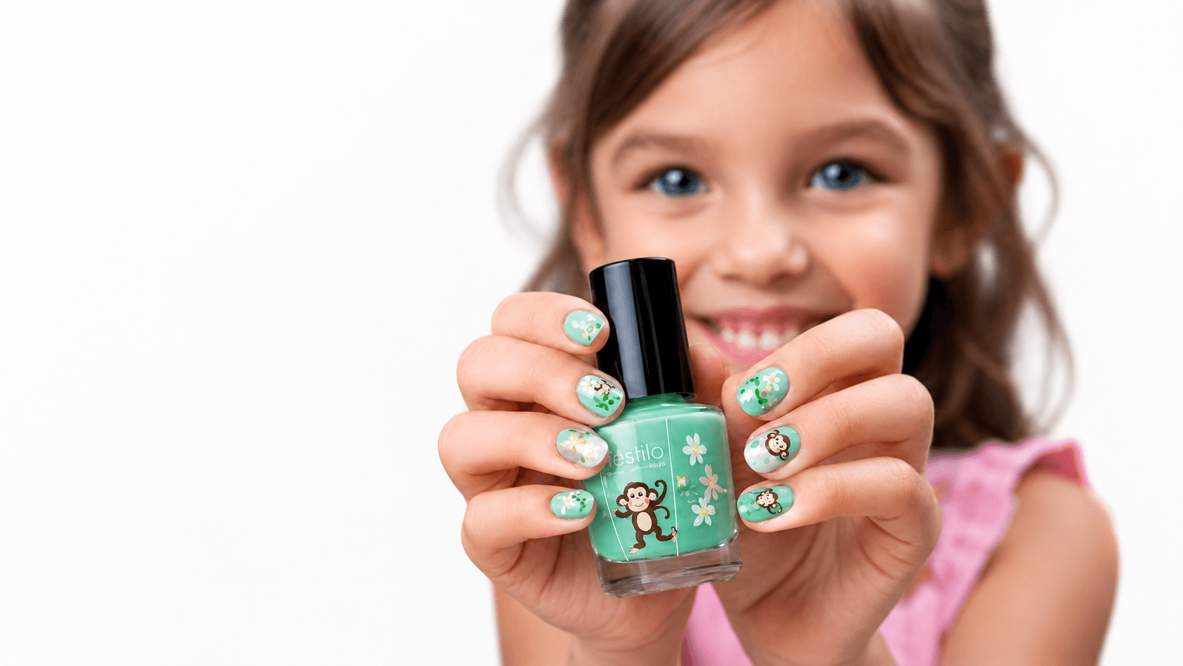 Smiling girl with green polish and decals on her nails, holding a kids' polish bottle — kids' manicure in Hialeah, FL