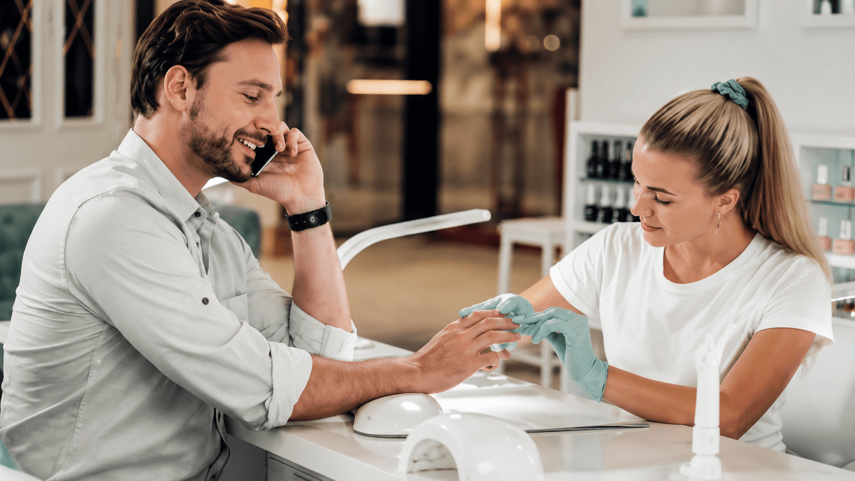 Man getting a manicure at a salon station while on the phone — men's services in Hialeah, FL
