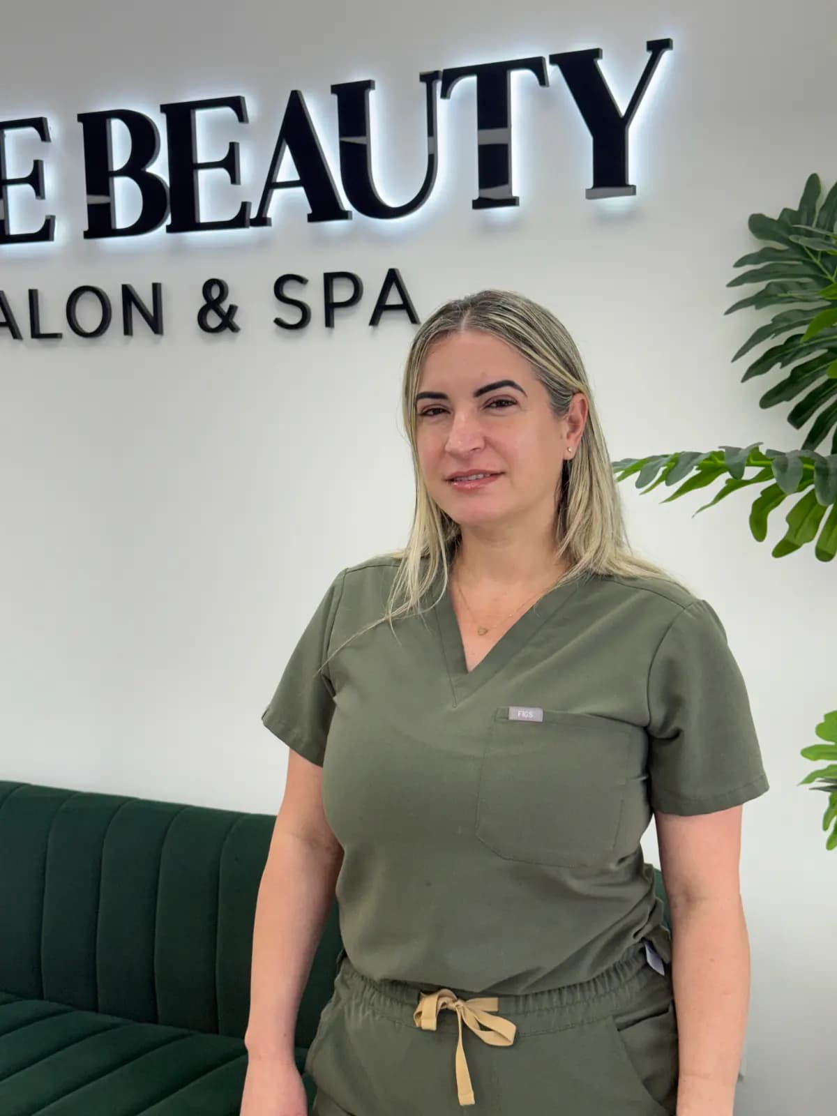 A technician from the Live Love Beauty Salon & Spa team beside the salon sign in Hialeah, FL